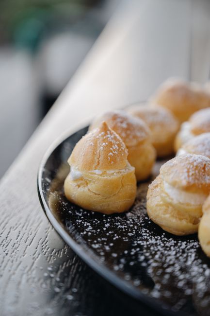 粉砂糖をまとった焼きたてのシュークリームの断面、白いクリームがたっぷり
