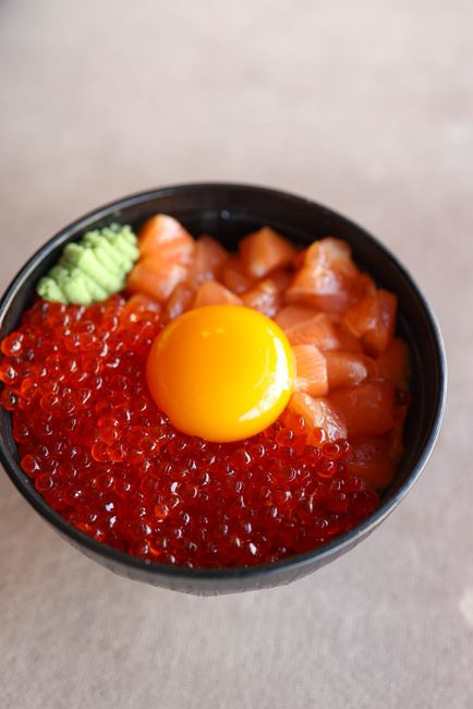 いくらとサーモン、卵黄を盛った丼を斜め上から撮影した写真