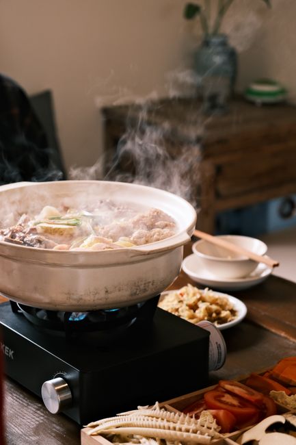 湯気の立つ土鍋を卓上コンロにのせた食卓の様子
