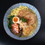 黒い器に入った塩ラーメン。透き通ったスープと具材を上から見た写真