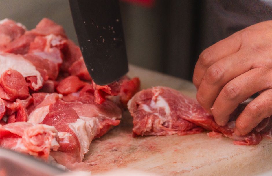 職人がまな板の上で丁寧に部位ごとへ処理する豚肉