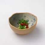 和風の陶器の小鉢に盛られた緑色の海藻サラダと赤い実
