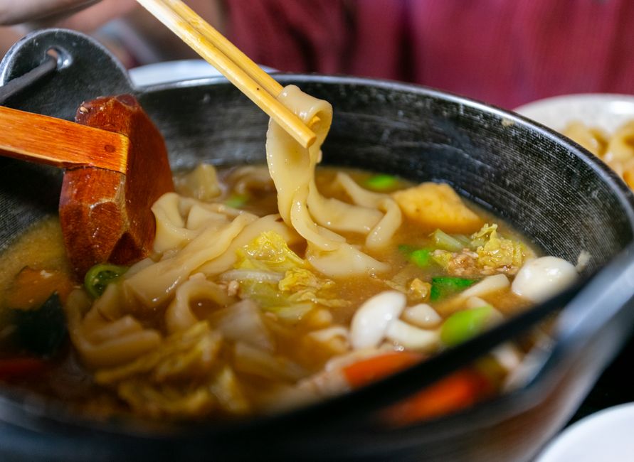 土鍋でうどんを箸で持ち上げている様子