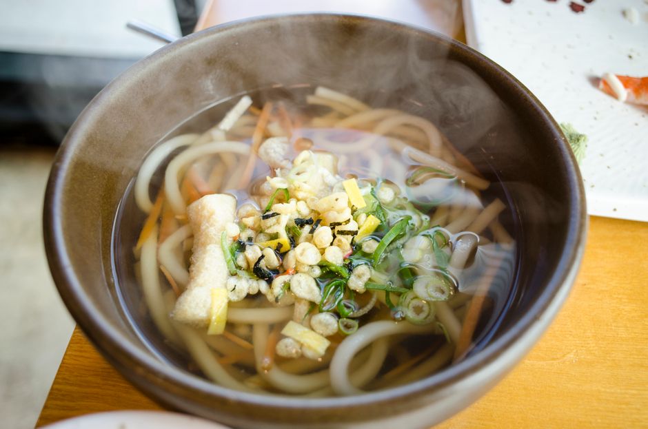 湯気の立つうどんに天かすとねぎをのせた一杯