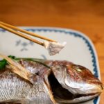 焼き上げた鯛を箸でほぐして食べている様子