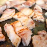 鉄板の上で焼かれる豚バラ肉のスライス