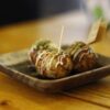 木のテーブルに置かれた皿の上のたこ焼き3個