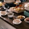 木のテーブルに並んだ土鍋と数種類の小皿料理