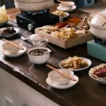 木のテーブルに並んだ土鍋と数種類の小皿料理