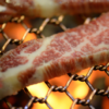 炭火の網で焼いている霜降り牛肉のクローズアップ