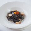 白い深皿に盛ったいか墨パスタと魚介
