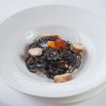 白い深皿に盛ったいか墨パスタと魚介
