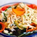 裂いた蒸し鶏をきゅうりと人参の上にのせたサラダ