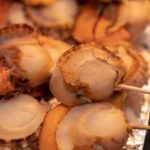 殻付きホタテを串に刺して炭火で焼く様子