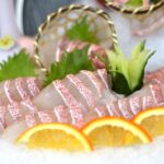 氷の上に盛られた白身魚の刺身と輪切りのオレンジ、大葉