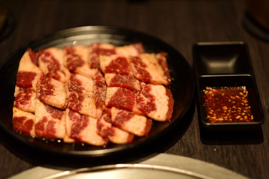 霜降りの牛肉を焼肉用にカットしてタレと共に並べた写真