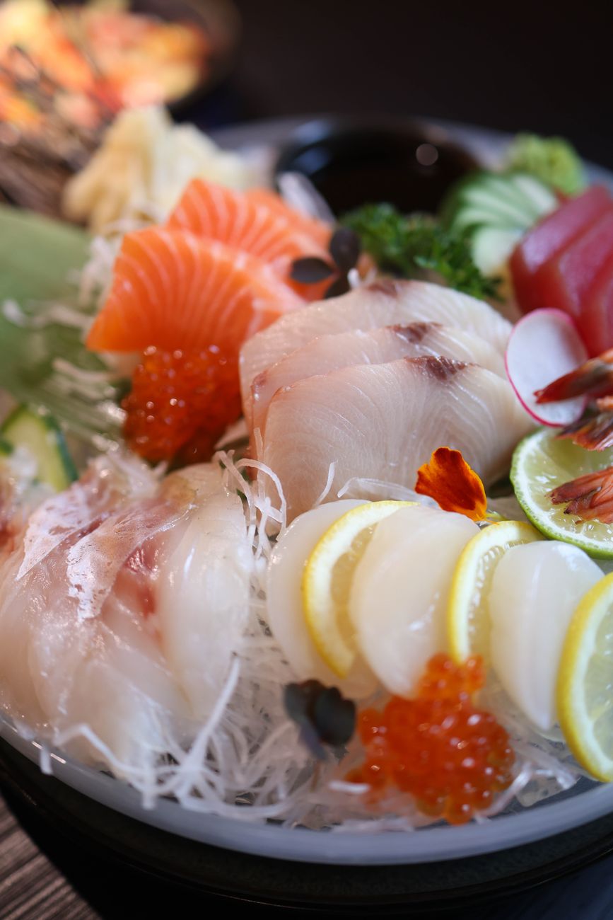 大根のつまを敷いた皿に、白身魚やサーモン、まぐろの刺身、いくら、レモンが彩りよく盛り付けられている