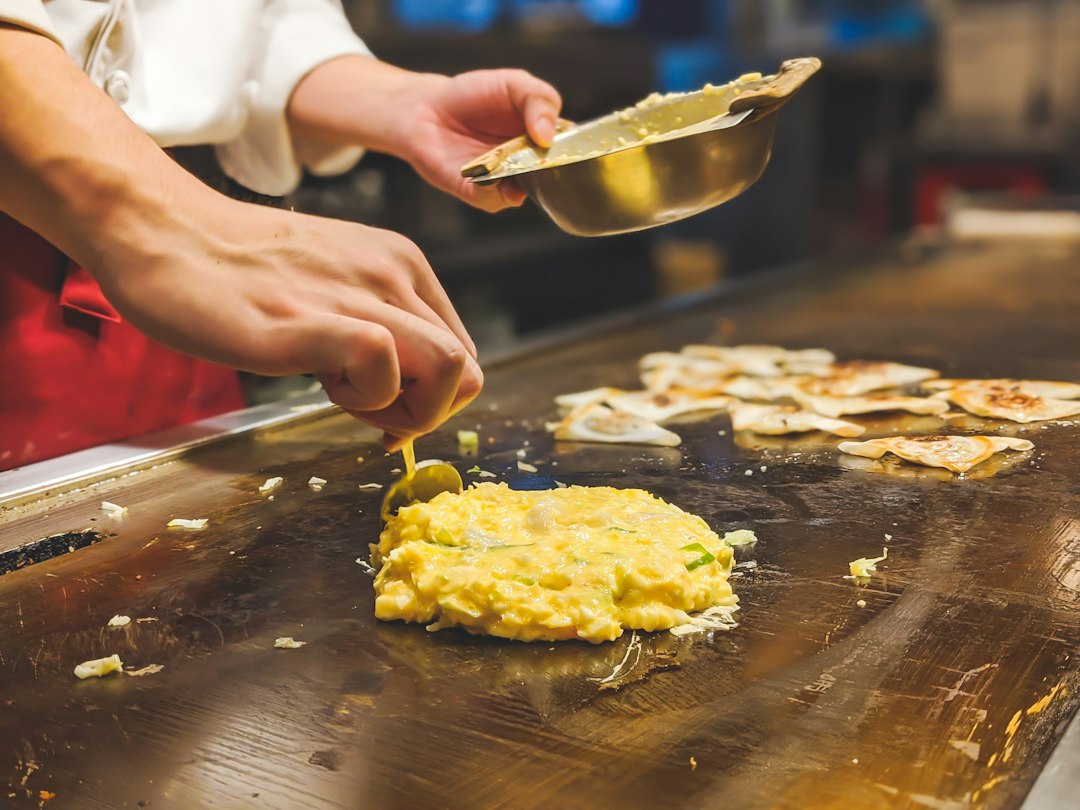 鉄板でお好み焼きの生地を仕上げる職人の手元