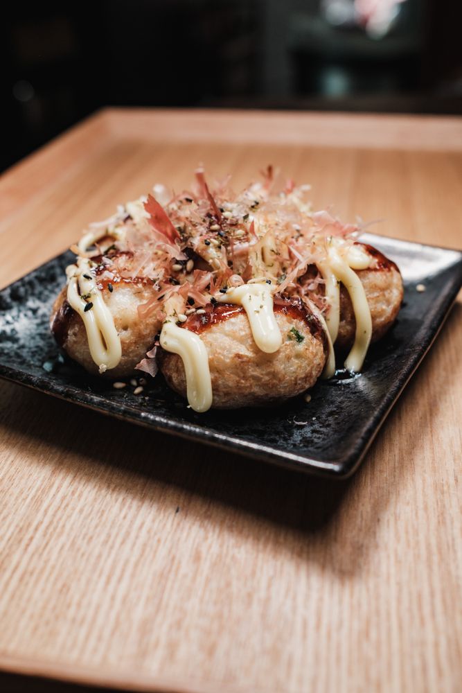 黒い皿に盛られたたこ焼きにマヨネーズと鰹節をトッピング