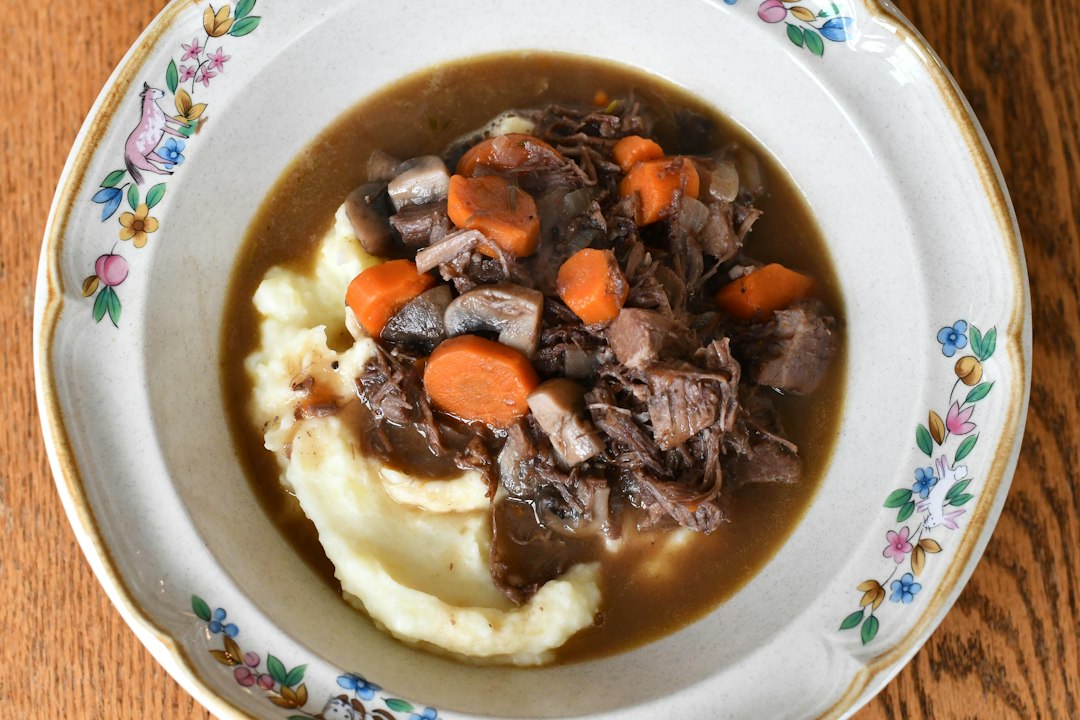 白い皿に盛った牛肉とにんじん、玉ねぎが入ったビーフシチュー