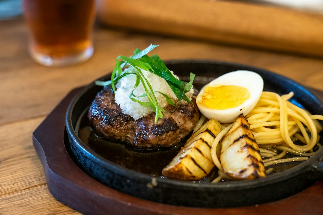 鉄板にのせたハンバーグとフライドポテト、いんげんの付け合わせ