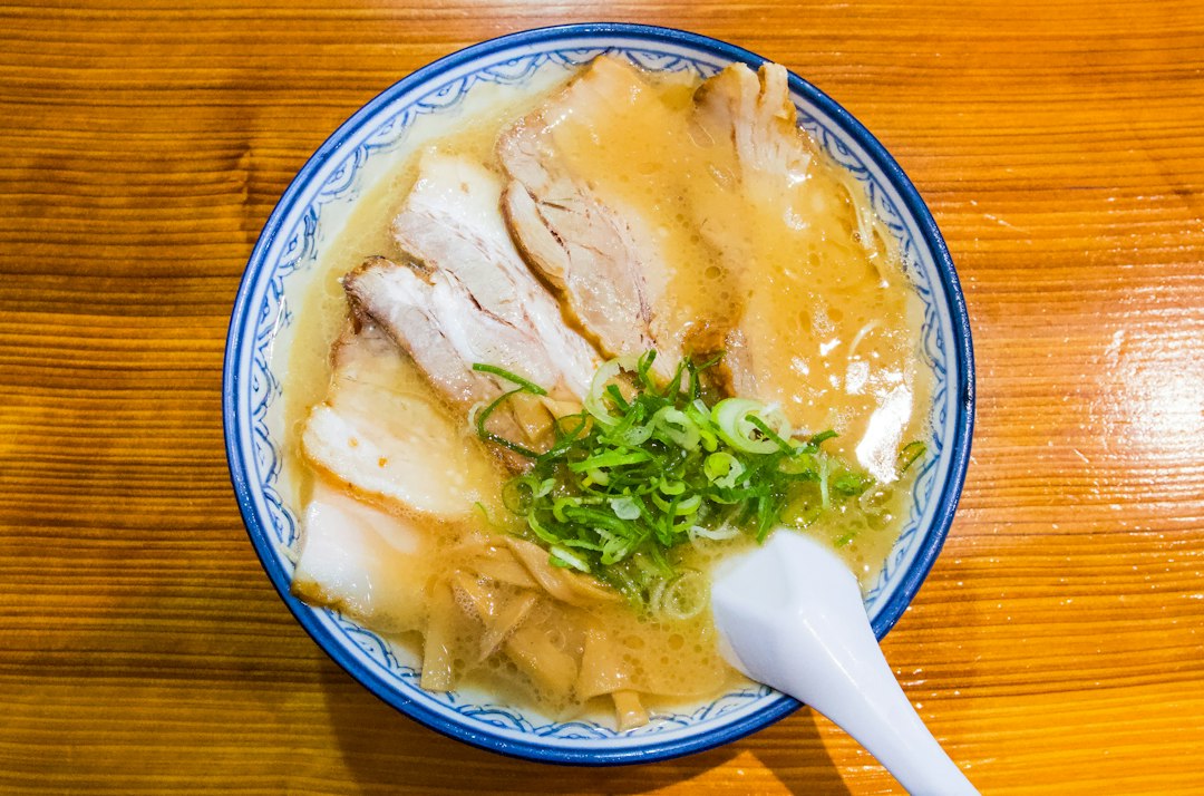 青い縁の器に盛った豚骨ラーメンとチャーシュー、ねぎ