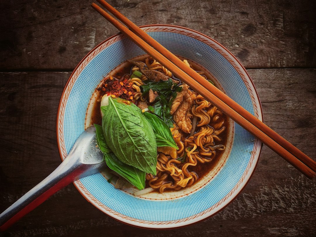 青い器に盛ったラーメンと、スプーン、箸