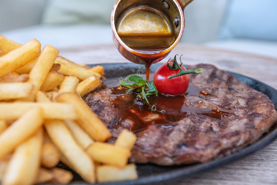 肉料理に茶色いソースを注いでいるところ