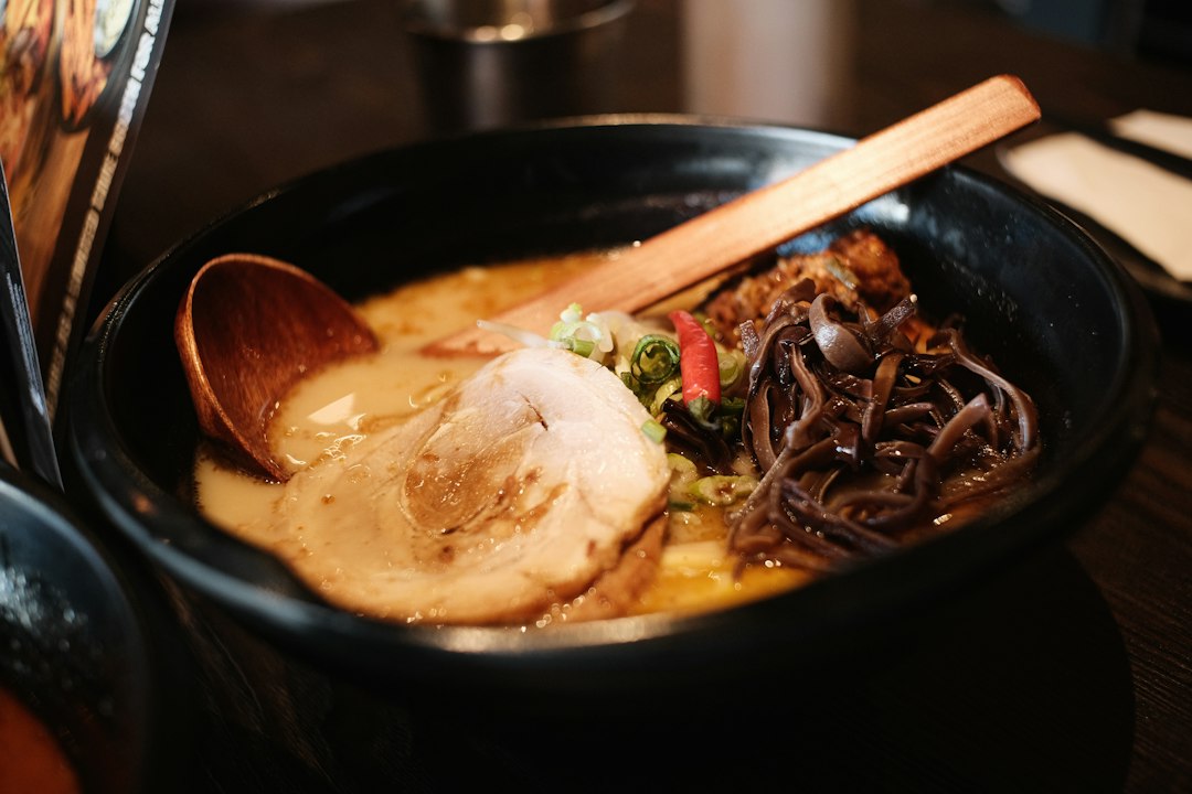 チャーシューをのせたラーメンを木のさじですくうところ