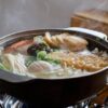 ちくわぶやしいたけ、えのきが入ったおでん鍋から湯気が立つ様子