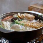ちくわぶやしいたけ、えのきが入ったおでん鍋から湯気が立つ様子