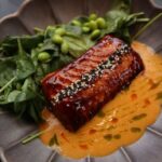 艶やかな照り焼き風のたれがかかった魚の切り身を青菜と枝豆とともに盛り付けた様子