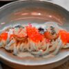黒いパスタに焼きホタテといくらを乗せた一皿のクローズアップ