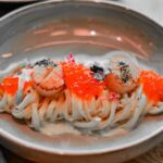 黒いパスタに焼きホタテといくらを乗せた一皿のクローズアップ