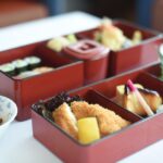 赤い漆器の重箱に盛られた複数の和食料理