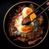 箸で牛肉をつまみ上げる牛丼のクローズアップ