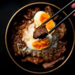 箸で牛肉をつまみ上げる牛丼のクローズアップ