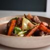 白い皿に盛った牛肉とにんじん、玉ねぎが入ったビーフシチュー