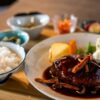 ごはんと小鉢が並ぶ定食スタイルで盛り付けたデミグラスソースのハンバーグ