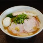 白い器に盛った塩ラーメンとチャーシュー、ねぎ、半熟卵