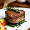 白い皿にのせたヒレステーキとローズマリー、焼き野菜