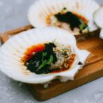 木の板にのせた殻付きホタテと青菜