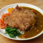 揚げたてとんかつにカレーソースを添えた一皿