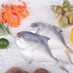 氷の上に並べた新鮮な魚介類と海老、ホタテ、レモンとローズマリー