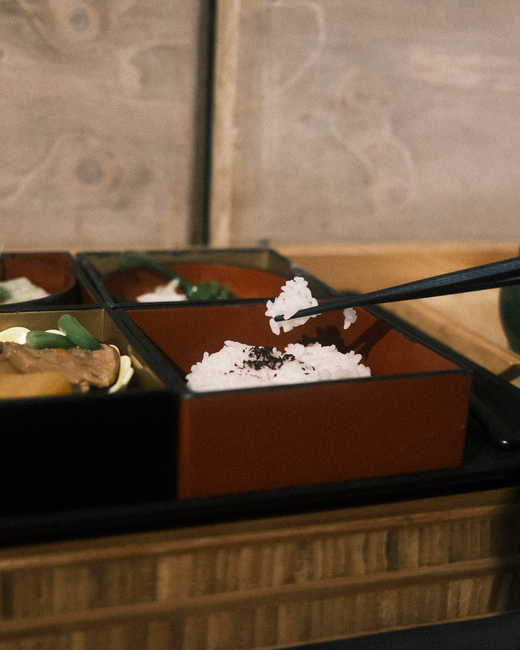 箸でご飯をつまむ重箱料理のクローズアップ