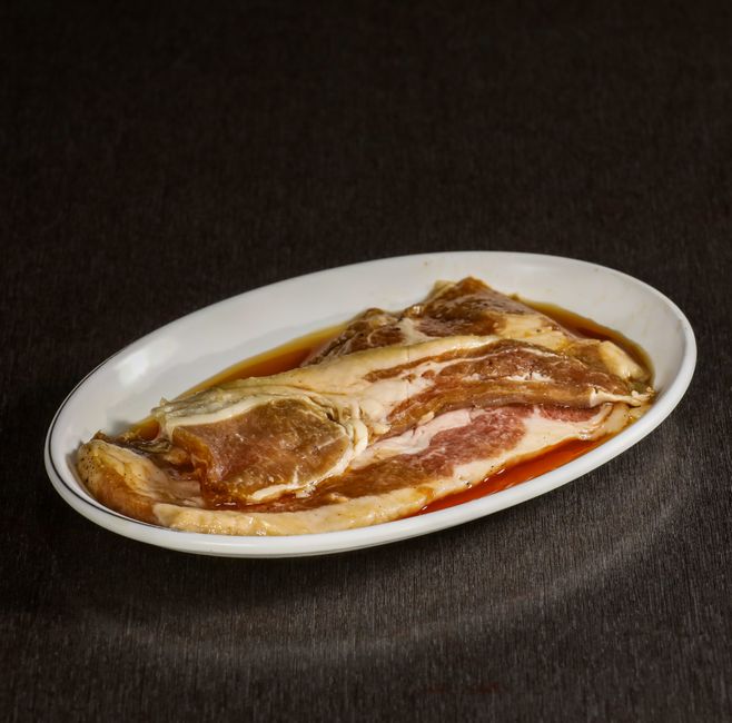 皿に並べた生の豚バラ肉薄切りのクローズアップ